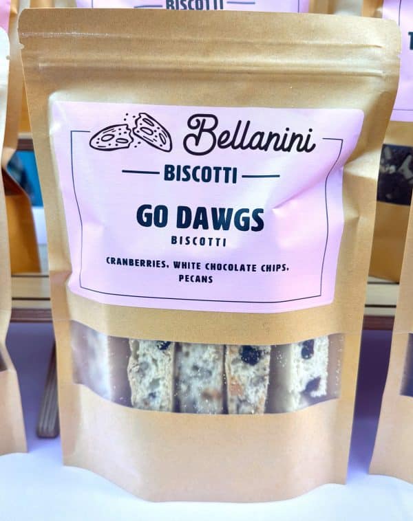 A brown paper bag with a clear window showing biscotti inside; label reads Bellanini Biscotti Go Dawgs Biscotti with cranberries, white chocolate chips, and pecans.